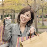 Asian woman walk and hold shopping bags at street after raining